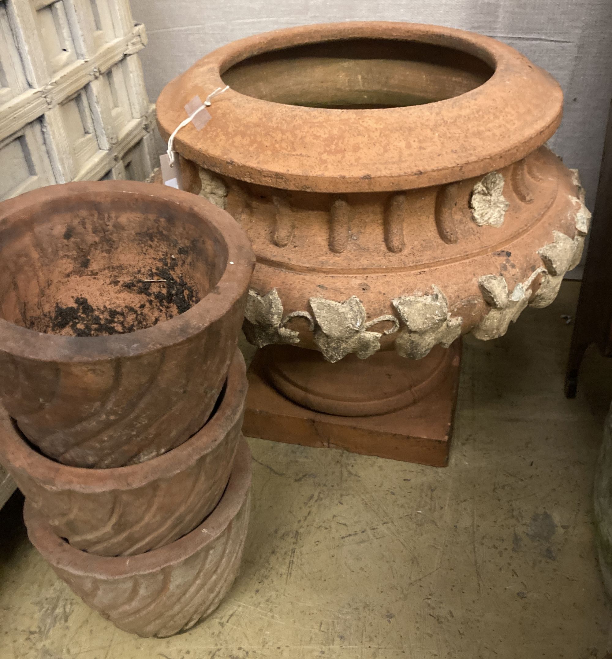 A circular terracotta garden planter on stand, diameter 56cm, height 50cm together with three smaller terracotta garden planters